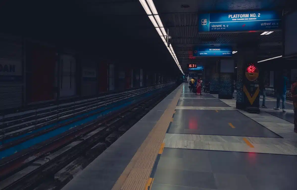 Stazione ferroviaria con persone in attesa su un binario afoso
