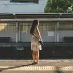 Donna sola su un binario ferroviario in una giornata afosa, con margherite in mano
