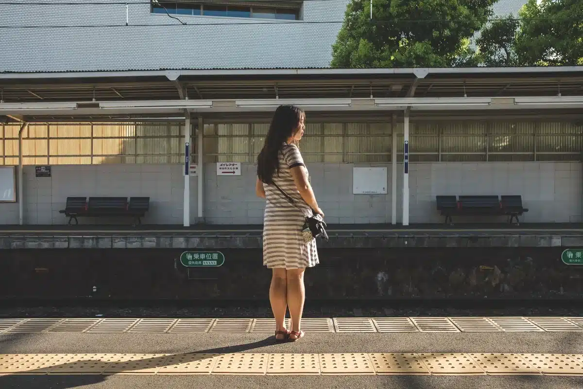 Donna sola su un binario ferroviario in una giornata afosa, con margherite in mano