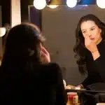 Un'attrice in trasformazione tra due ruoli contrapposti, illuminata da una luce teatrale di scena.