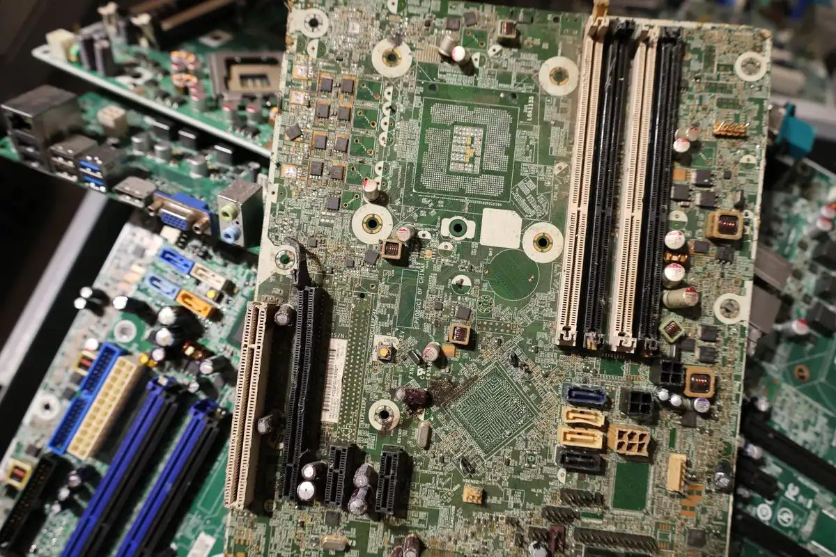 Componenti elettronici riciclabili e batterie ricaricabili disposte su superficie neutra.