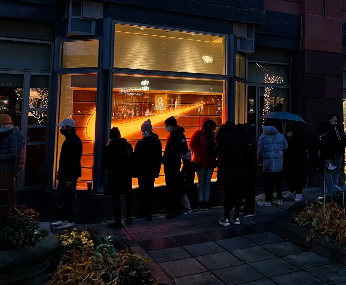 Folla di persone in coda per l'acquisto di capi streetwear in una piazza urbana