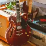 Mani su tastiera di chitarra elettrica in studio di registrazione con amplificatore sullo sfondo