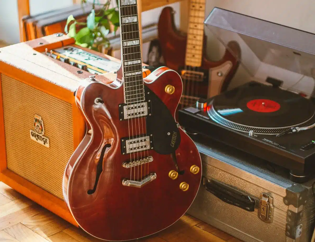 Mani su tastiera di chitarra elettrica in studio di registrazione con amplificatore sullo sfondo