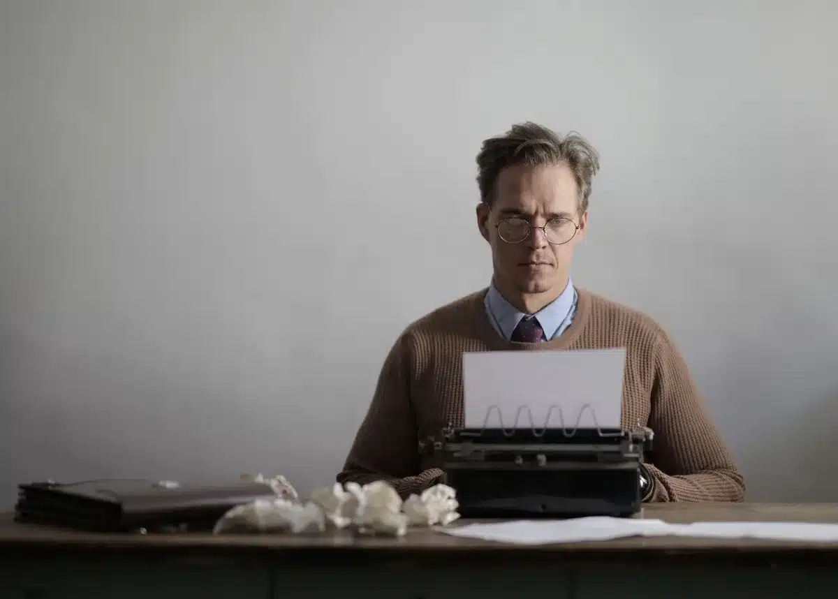 Una persona seduta a una scrivania con un foglio e una penna, in un momento di introspezione e scrittura personale
