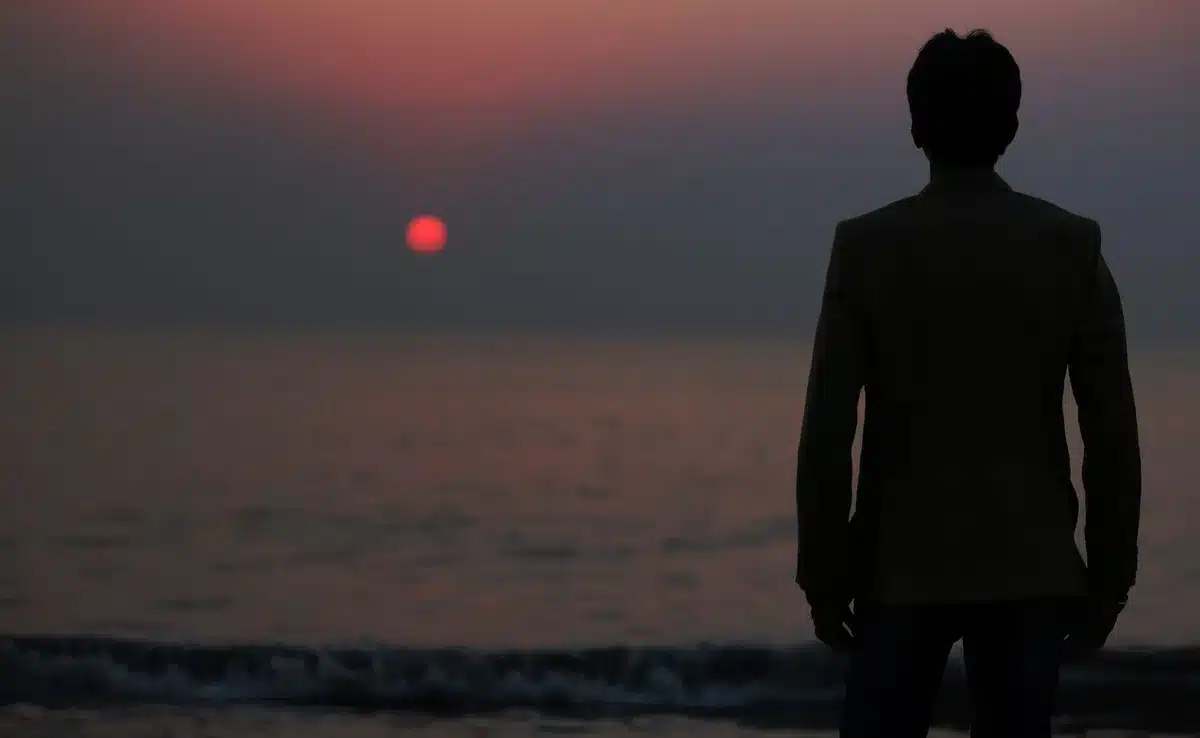 Figura solitaria contempla il tramonto su una spiaggia estiva