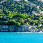 Coppia che cammina lungo una spiaggia mediterranea soleggiata con villa sullo sfondo