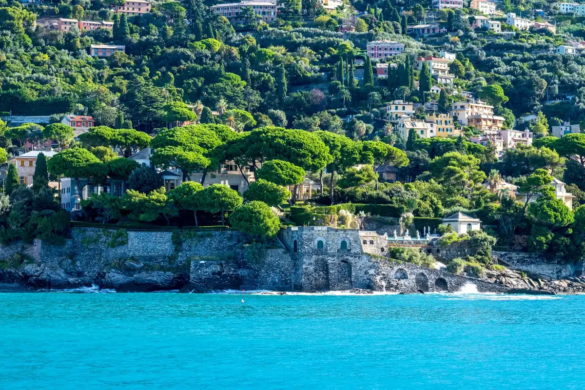Coppia che cammina lungo una spiaggia mediterranea soleggiata con villa sullo sfondo