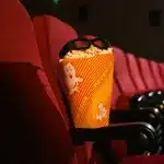 Spettatore di spalle guarda uno schermo cinematografico gigante illuminato in una sala buia