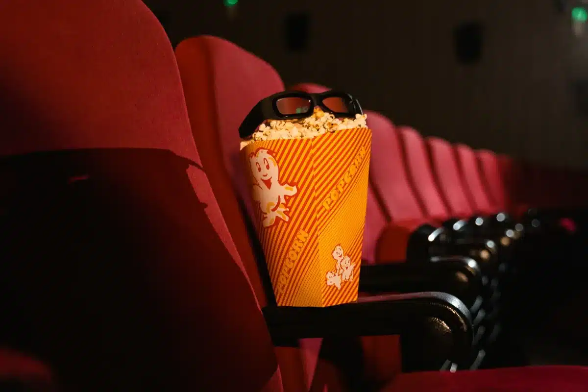 Spettatore di spalle guarda uno schermo cinematografico gigante illuminato in una sala buia