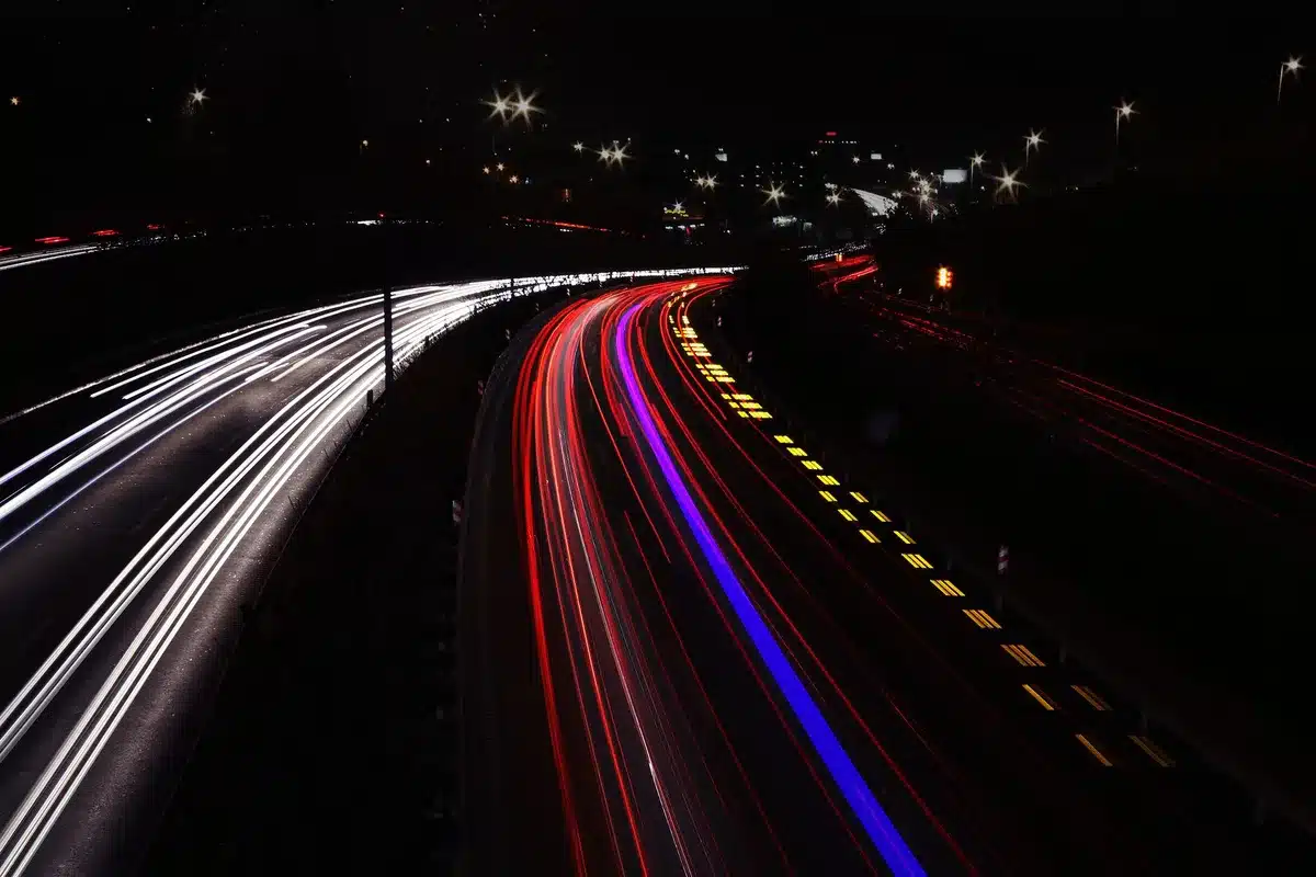 Autostrada deserta di notte illuminata da luci al neon, che evoca l'estetica synthwave e il mondo sonoro di Kavinsky