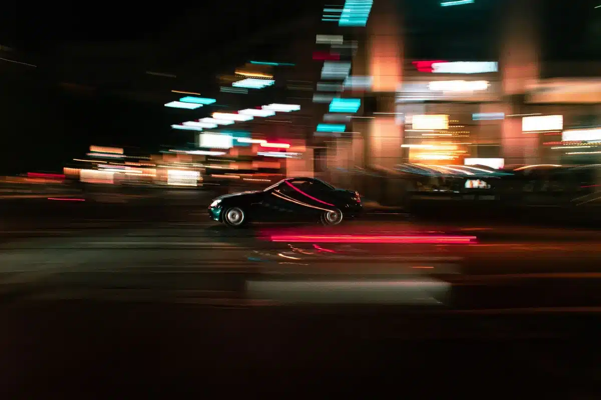 Figura silenziata al volante di notte con luci neon blu e rosa, atmosfera retrò anni Ottanta