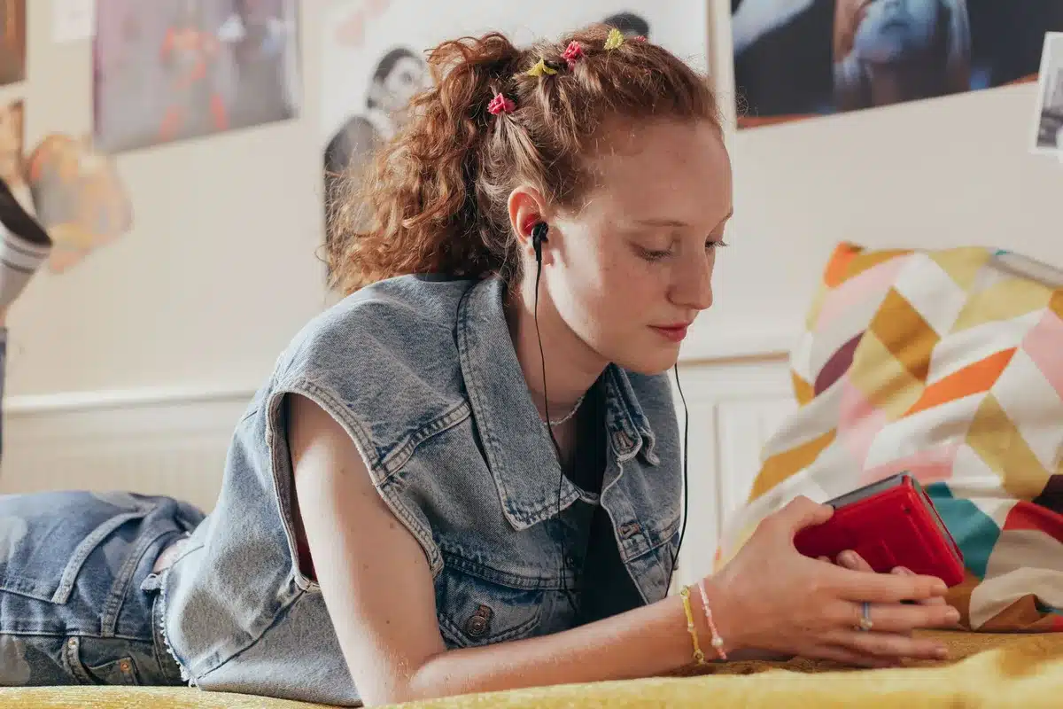 Adolescenti in una stanza mentre ascoltano musica insieme, circondati da cassette e oggetti personali.