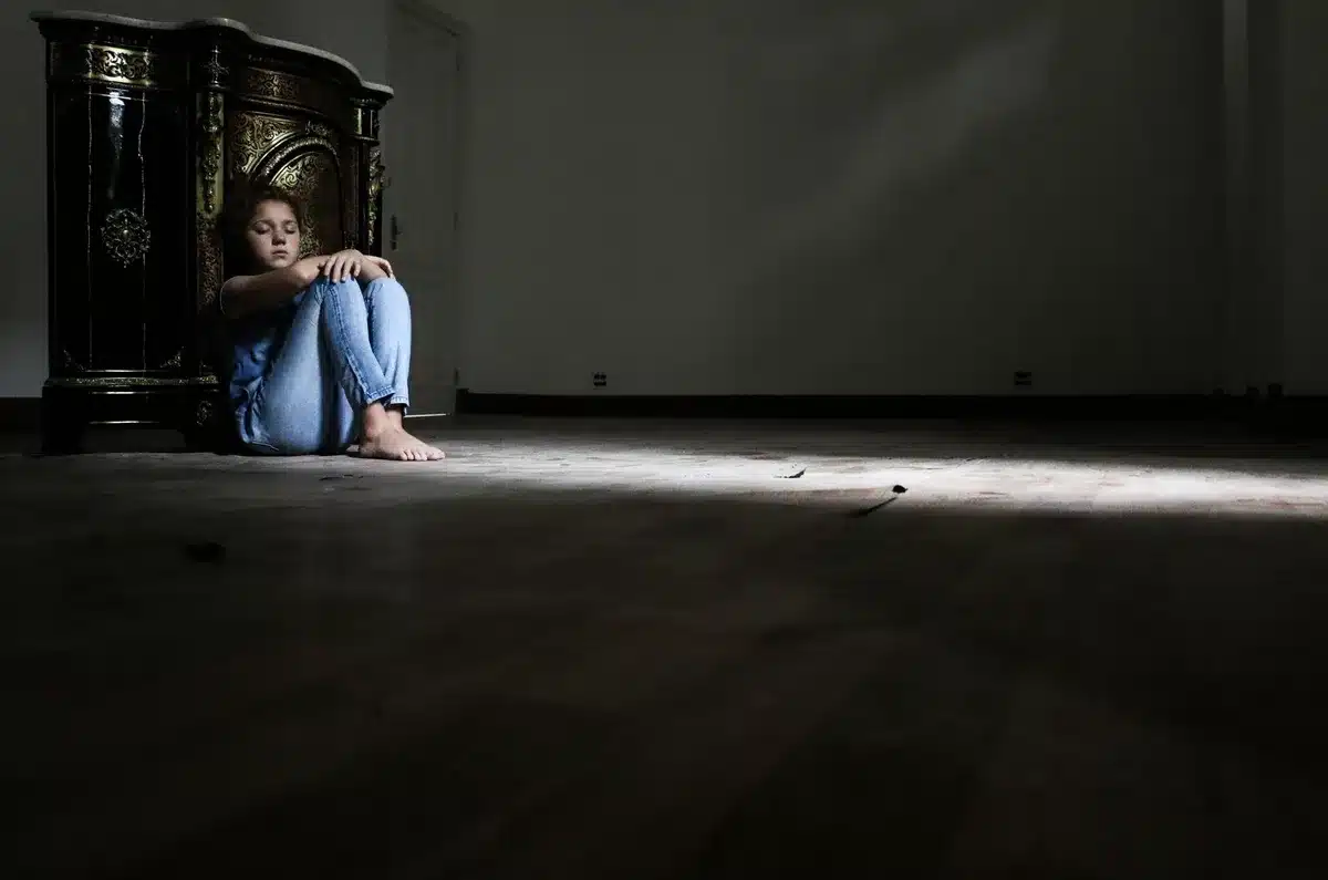 Una persona sola in uno spazio interno tranquillo e minimalista, seduta in contemplazione consapevole.
