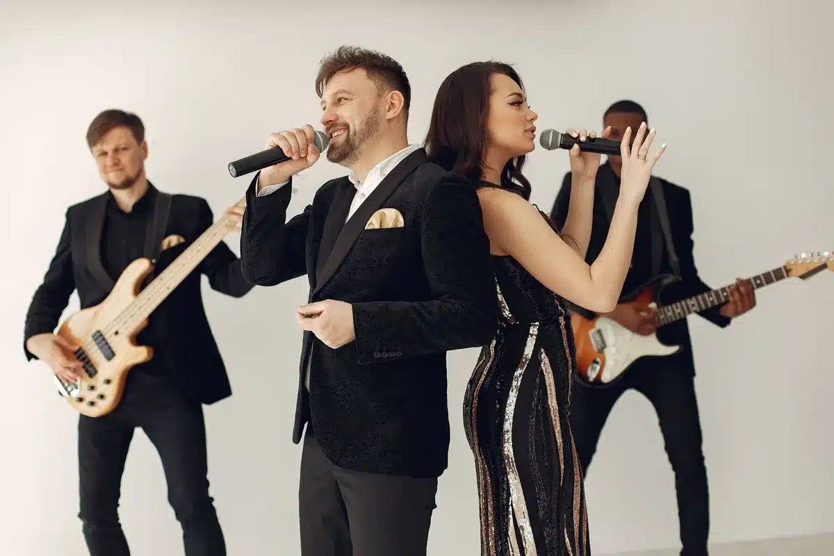 Tre cantanti in coordinato sul palco di uno stadio internazionale durante una performance