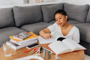 Donna seduta da sola tra libri aperti, volto girato, tra ombra e luce