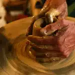 Mani che tengono un paio di occhiali da sole con montatura arrotondata e forme scultoree
