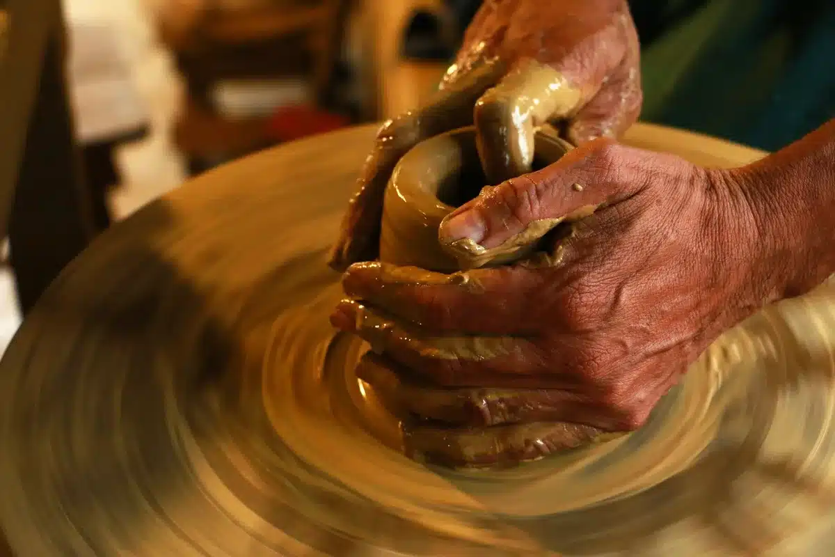 Mani che tengono un paio di occhiali da sole con montatura arrotondata e forme scultoree