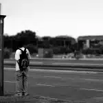 Figura solitaria in piedi su una strada urbana vuota al tramonto, circondata da luci lontane