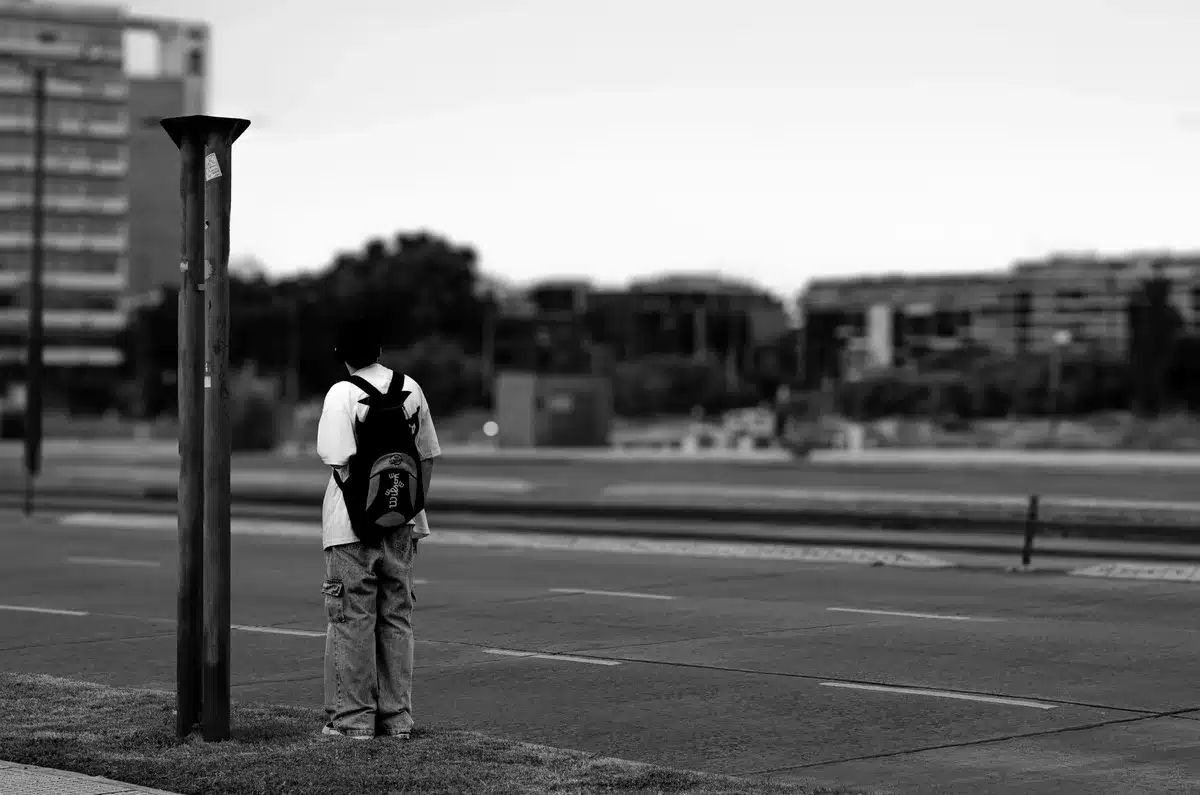 Figura solitaria in piedi su una strada urbana vuota al tramonto, circondata da luci lontane
