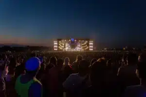 Palco esterno di festival estivo con folla di spettatori e luci serali in una piazza