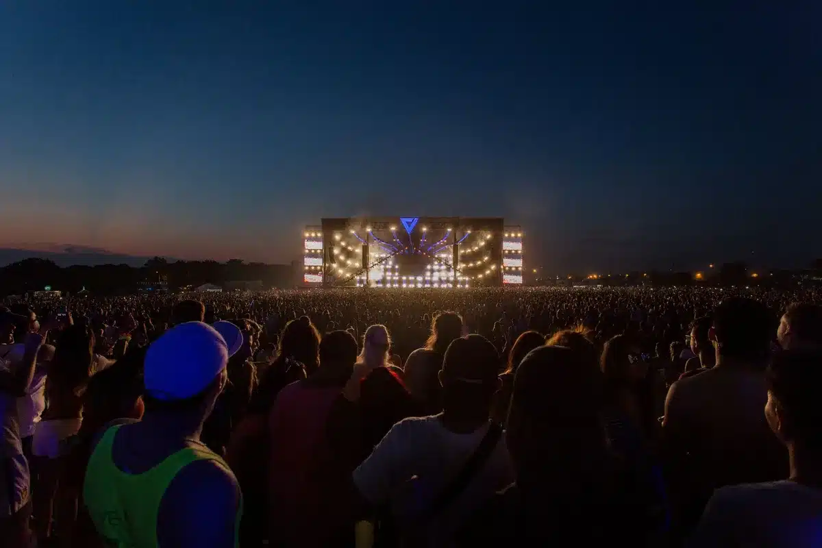 Palco esterno di festival estivo con folla di spettatori e luci serali in una piazza