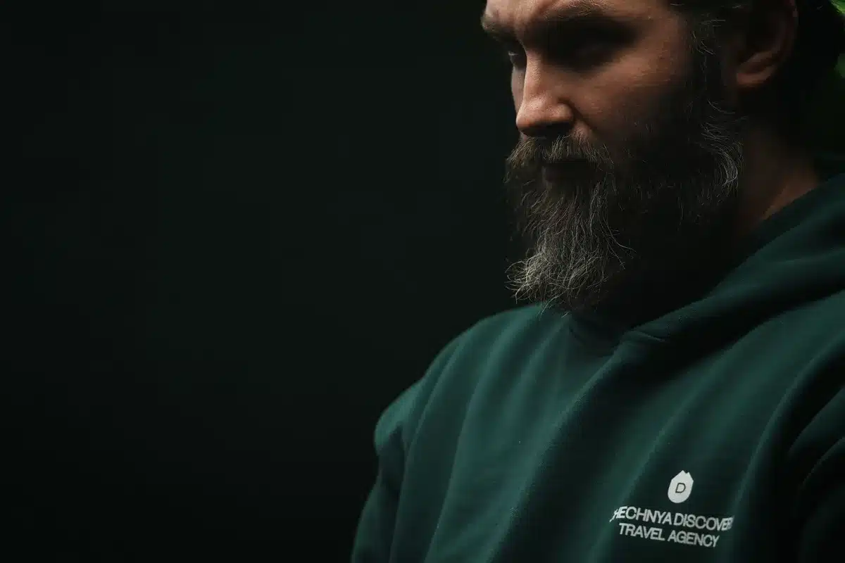 Volto stanco di un uomo con barba lunga e sguardo consumato, incarnazione dell'eroe logoro