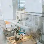 Mani che assemblano componenti robotici su un banco di lavoro industriale con circuiti e attrezzi di precisione