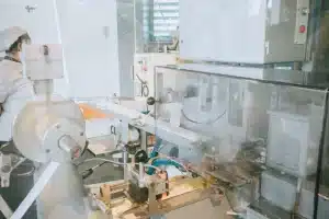 Mani che assemblano componenti robotici su un banco di lavoro industriale con circuiti e attrezzi di precisione