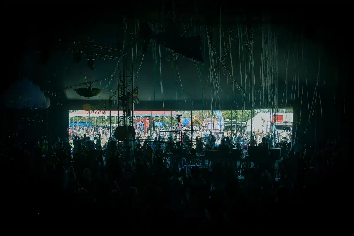 Artisti anonimi sul palco di un festival musicale con il pubblico che balla davanti