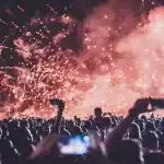 Folla di spettatori con le mani alzate durante un concerto in una venue all'aperto sul mare di sera