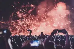 Folla di spettatori con le mani alzate durante un concerto in una venue all'aperto sul mare di sera