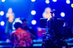 Troupe di produzione cinematografica allestisce luci e telecamere su un palco da concerto con strumenti musicali