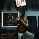 Cantante in silhouette su palco festival con chitarra acustica, folla sullo sfondo al tramonto
