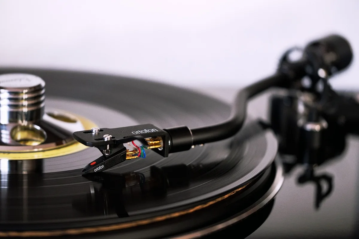 Vinile e giradischi accanto a cuffie e schermo che mostra una piattaforma di streaming