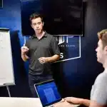 Tavolo d'ufficio con lavagna digitale, laptop chiuso e appunti adesivi