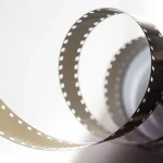 Silhouette of a film camera and vintage reels on an editorial desk with soft backlight