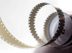 Silhouette of a film camera and vintage reels on an editorial desk with soft backlight