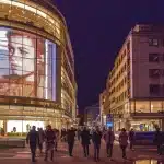 Berlina compatta ibrida parcheggiata in strada urbana con traffico sullo sfondo