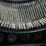 Tavolino con macchina da scrivere, lettere e pagine sparse in luce naturale
