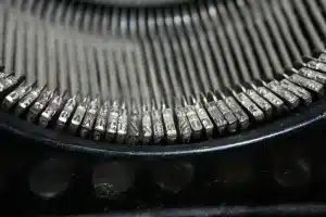 Tavolino con macchina da scrivere, lettere e pagine sparse in luce naturale