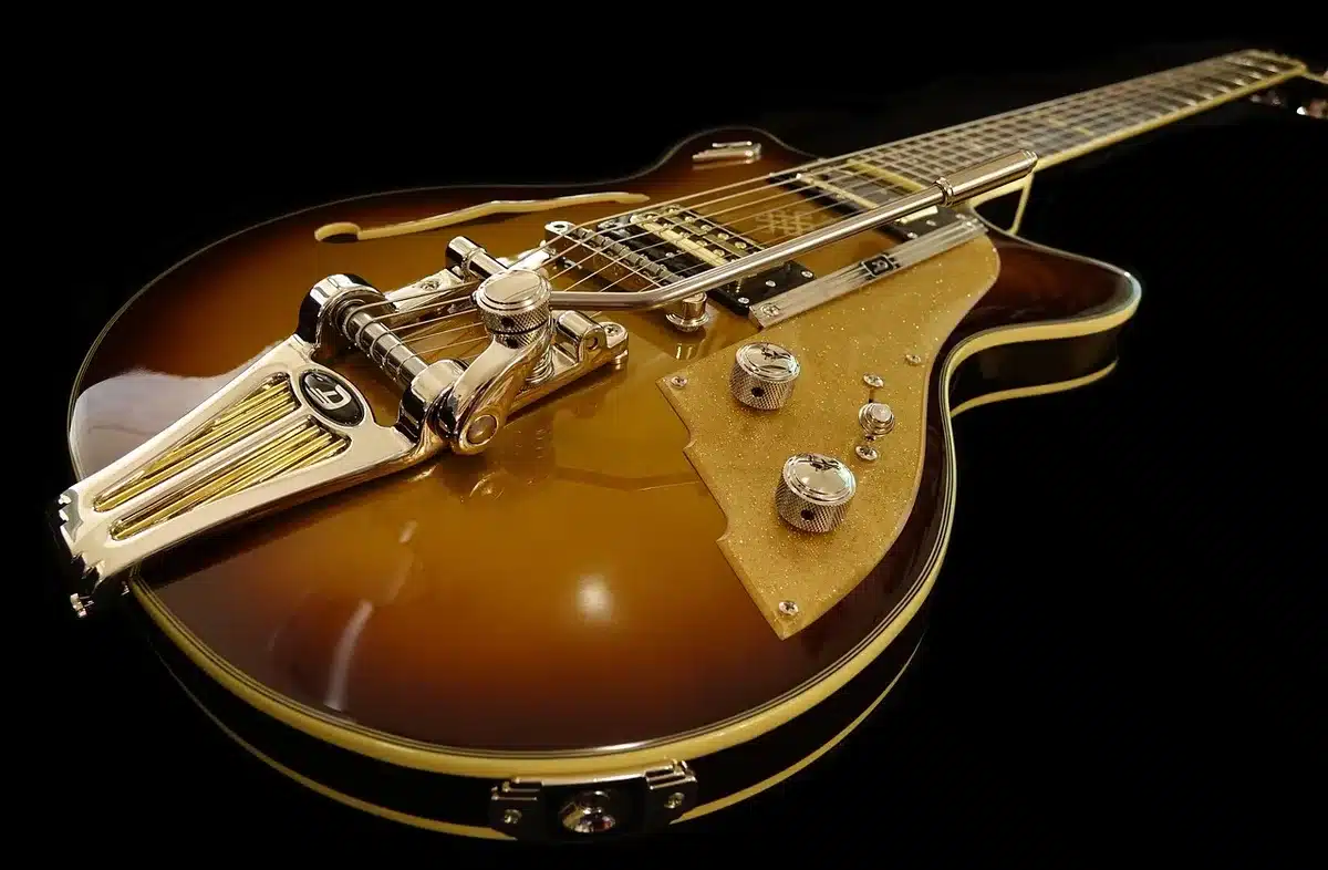 Mano che regge una chitarra acustica su un tavolo con foglio di testo