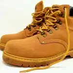 Coppia di scarpe in pelle e tessuto su marciapiede vicino a sentiero, con patina visibile