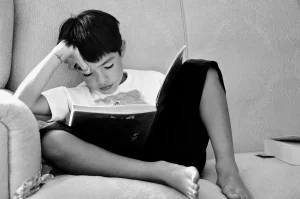 Mano anonima con e-reader e penna su scrivania con libri