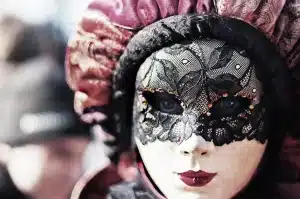 Silhouette anonima in tessuti ricomposti e maschera su sfondo neutro