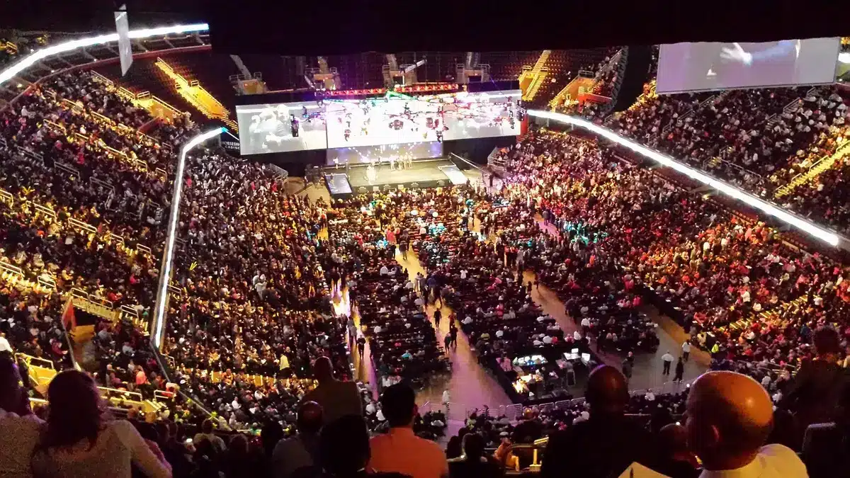 Palco di un'arena con luci e pubblico durante un concerto
