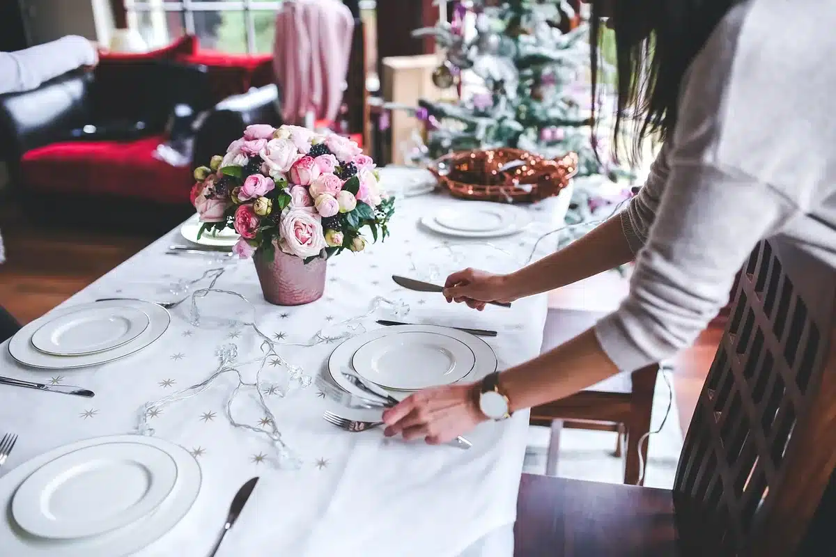 Tavolo da cena con calici e mani anonime visto dall'alto in una sala
