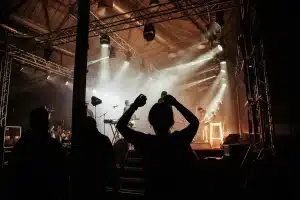 Folla anonima in piazza durante un concerto estivo con palco illuminato al tramonto