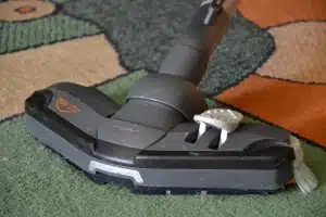 Scopa elettrica cordless in azione su pavimento in legno con particelle di polvere visibili