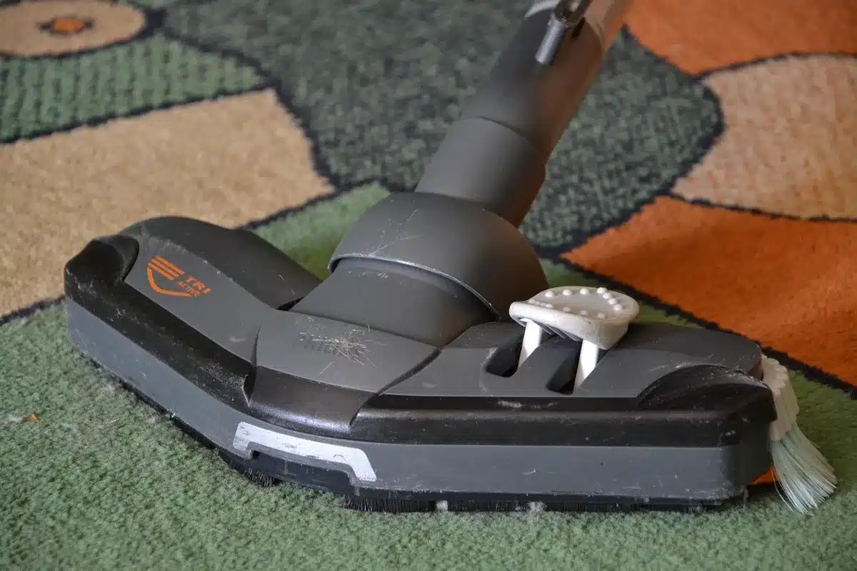 Scopa elettrica cordless in azione su pavimento in legno con particelle di polvere visibili